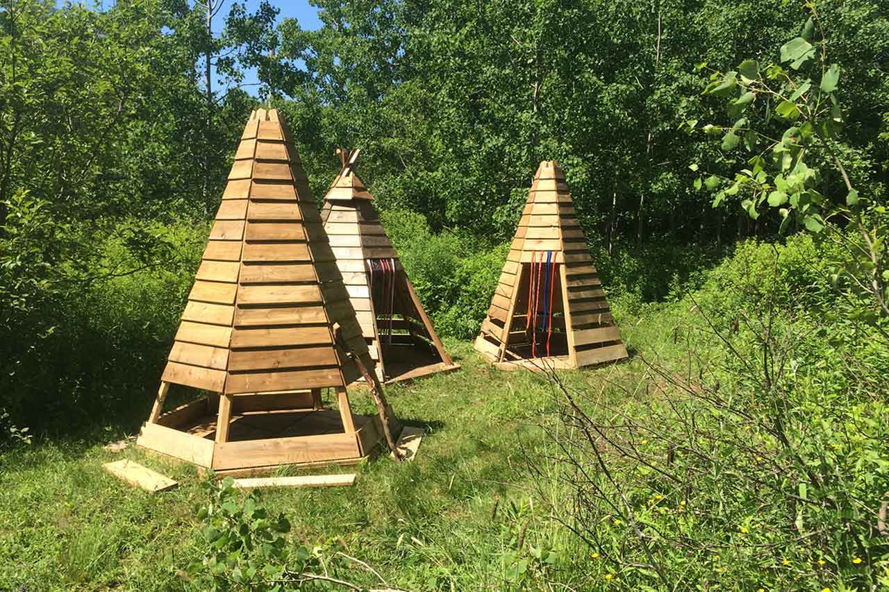 Three wooden play huts constructed outside.