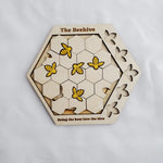 Hexagonal wooden puzzle titled 'The Beehive' with bee illustrations on a white background 1