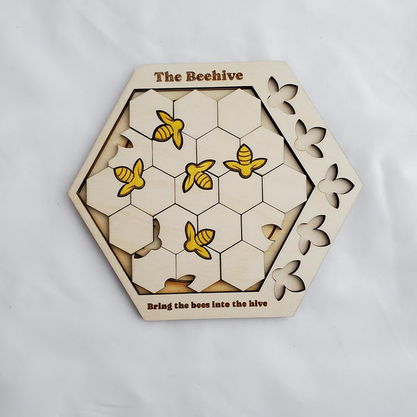 Hexagonal wooden puzzle titled 'The Beehive' with bee illustrations on a white background