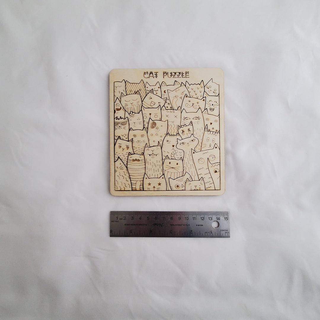 Cat-themed wooden puzzle on a white surface with a ruler for scale.