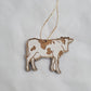 Wooden cow ornament on a string against a white background
