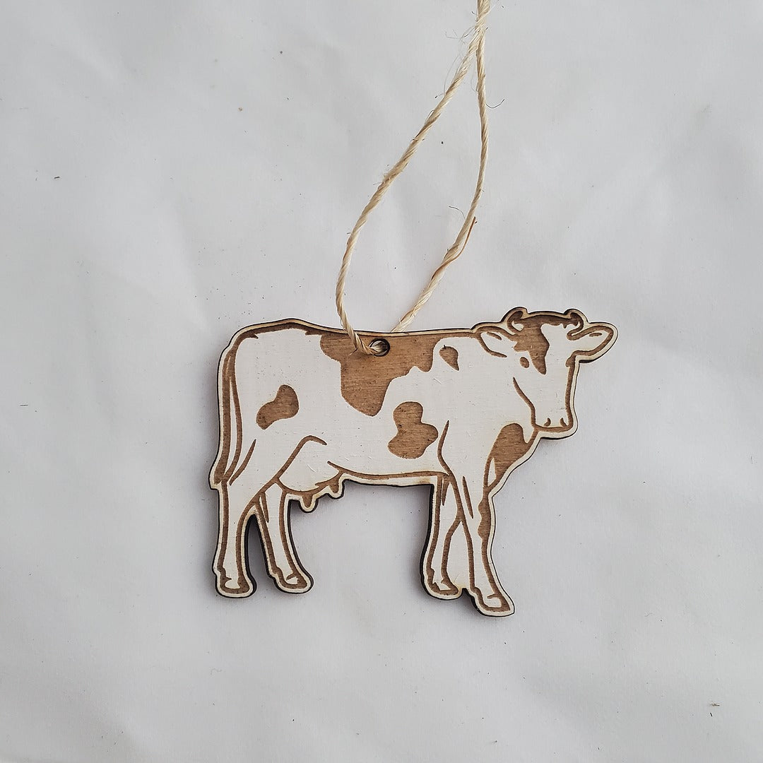 Wooden cow ornament on a string against a white background