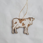 Wooden cow ornament on a string against a white background 3