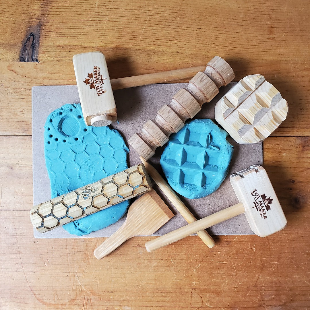 Set of wooden tools with blue  play dough on a wooden surface