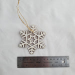 Wooden snowflake ornament with a ruler for scale on a white background 5
