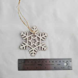 Wooden snowflake ornament with a ruler for scale on a white background