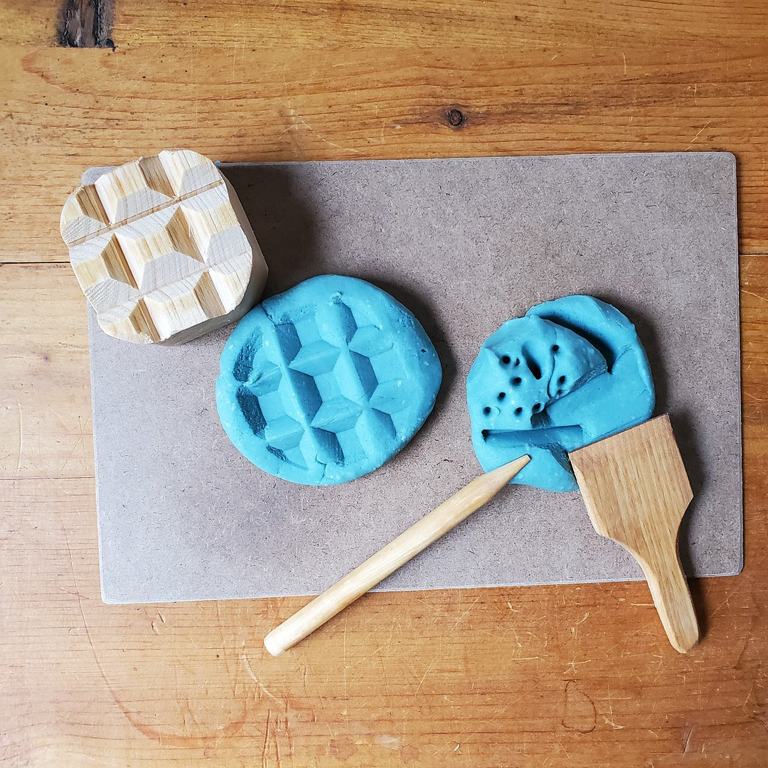 Blue play dough with wooden tools on a wooden surface