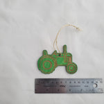 Green decorative tractor ornament with a string, next to a ruler for scale, on a white background 7